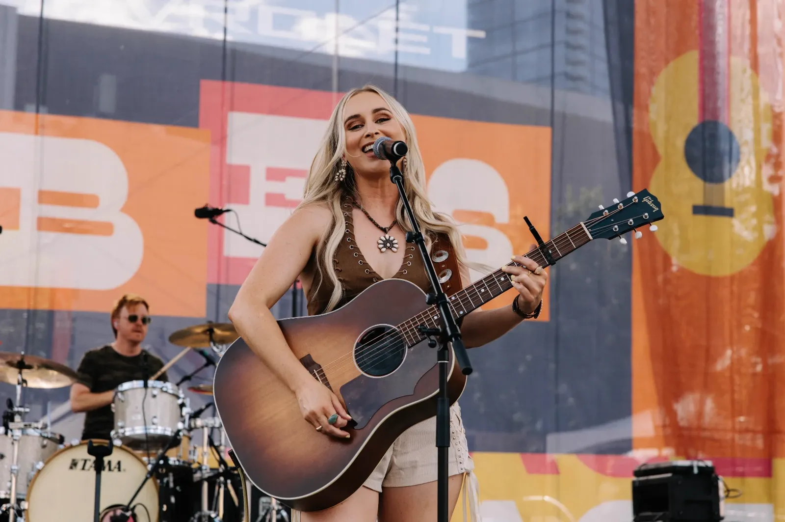 Melanie Dyer singing and playing guitar on stage with her band