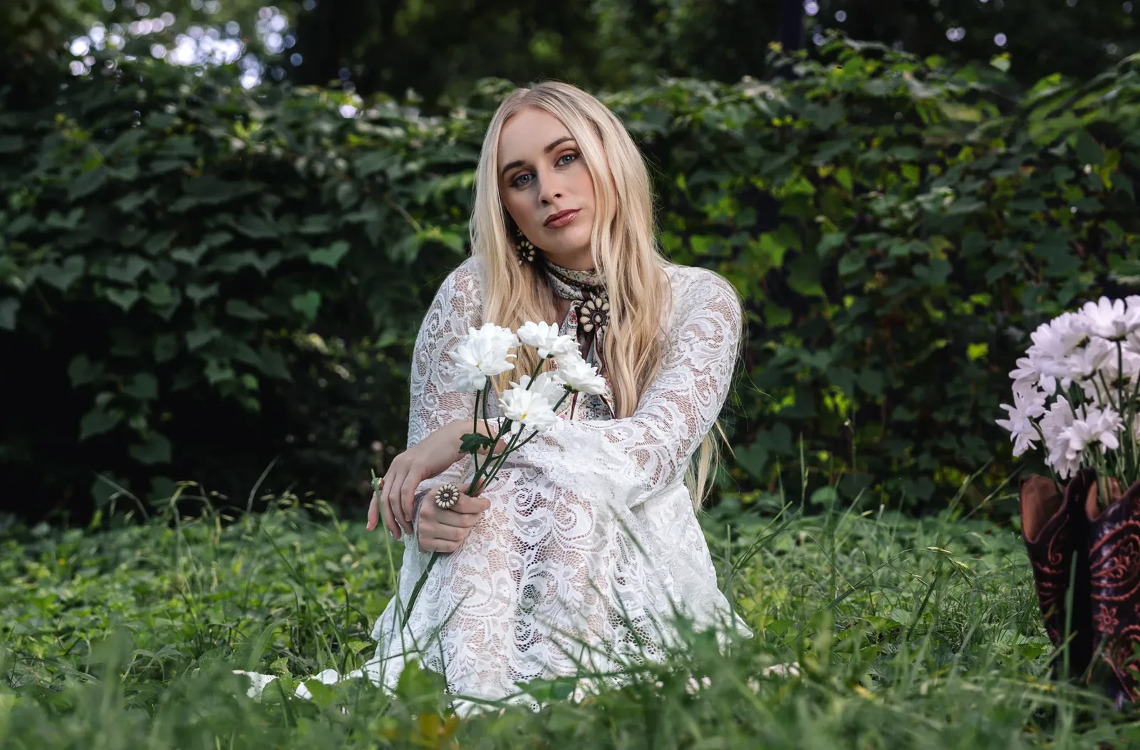 Melanie Dyer sitting in long grass holding daisies