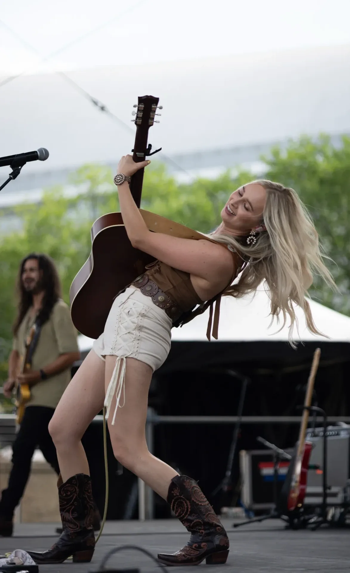 Melanie Dyer leaning back with her guitar on stage